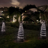 Decorative lighted trees in a garden setting with buildings in the background